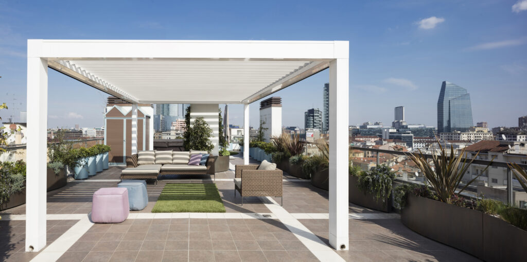 Elegante rooftop nel centro di Milano ospita la pergola Opera di Pratic e piante da balcone lungo tutto il perimetro della terrazza